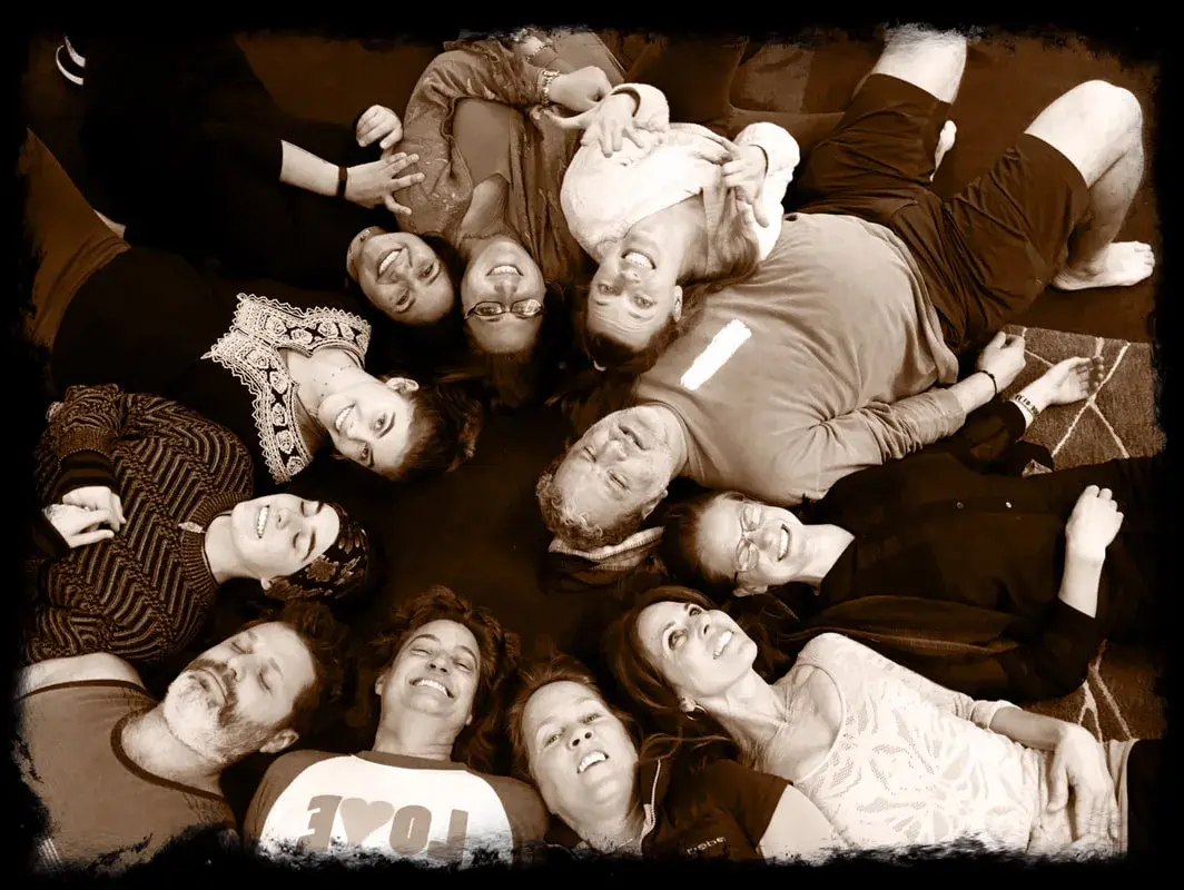 An Improv Playground class lying in a circle, heads together, laughing